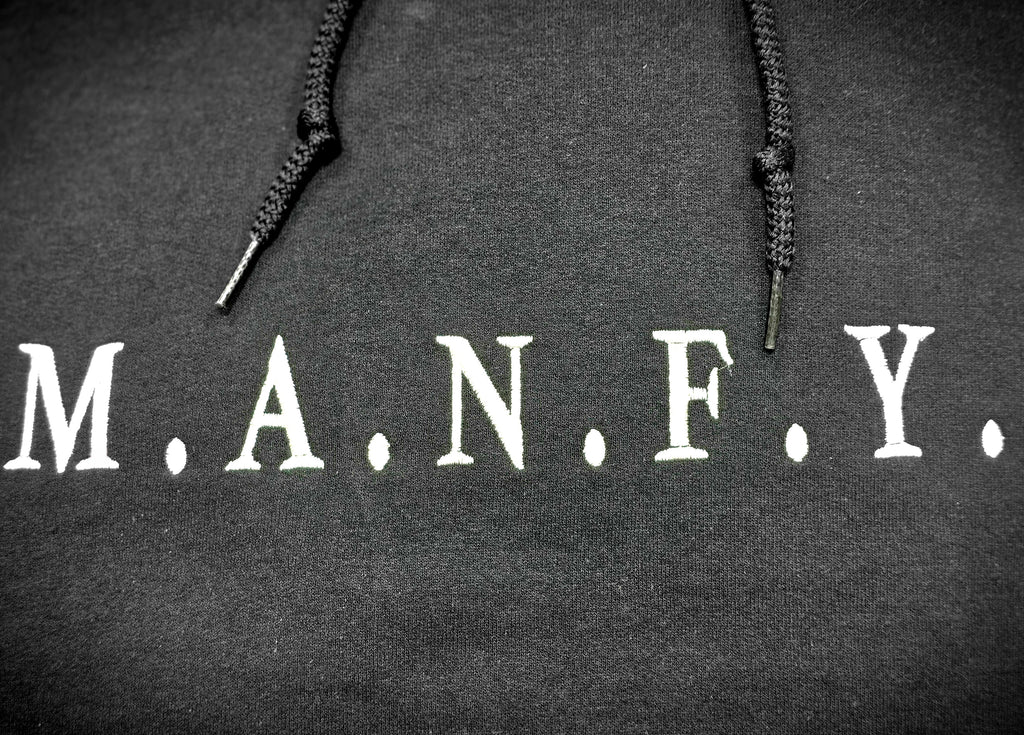 Close-up of premium white M.A.N.F.Y. embroidery stitched on black hoodie fabric
